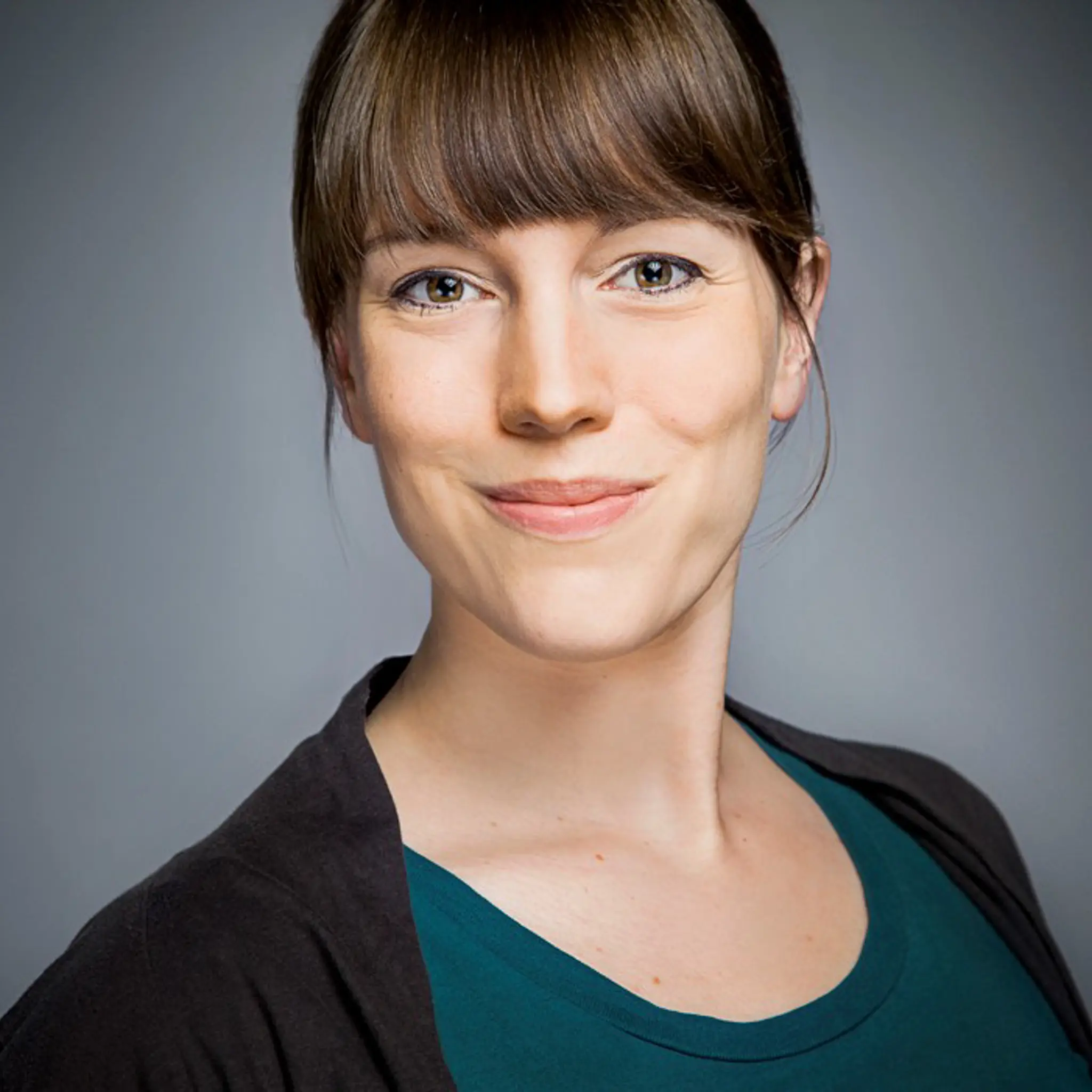 Porträt von Sara Josef, Frau mit braunen Haaren und grünem Oberteil lächelt.